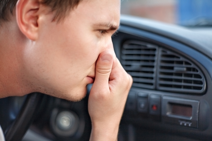 mężczyzna zatyka nos z powodu brzydkiego zapachu w samochodzie